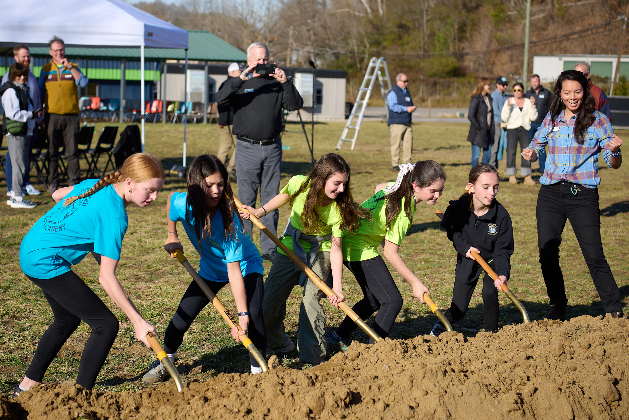 Students turn the first shovelfuls of dirt at the academic building groundbreaking event, cheered on by FBRA Girls Program Director Tricia Chan.