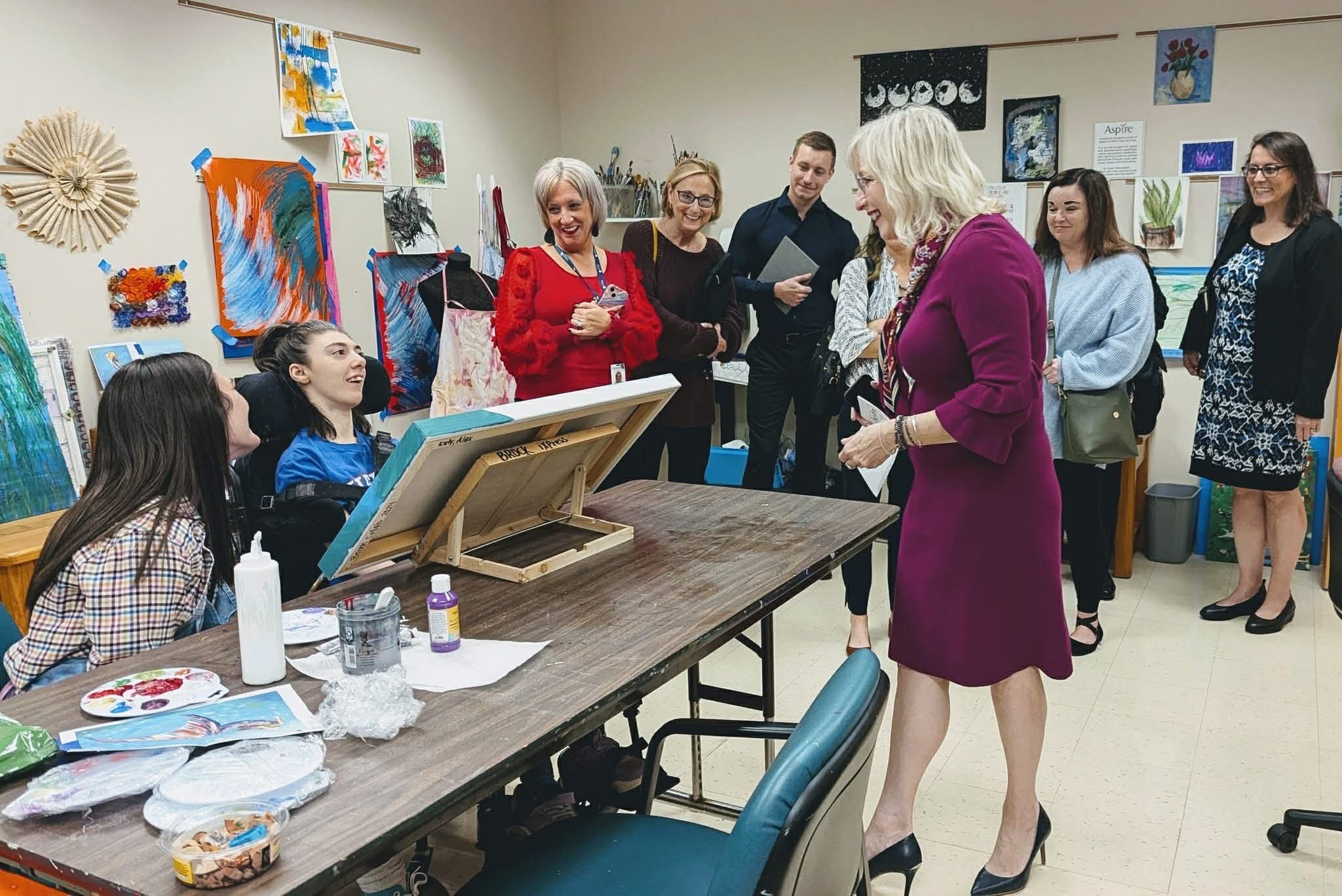 Resident Meghan Schobert (in red) visits Aspire’s art studio, where individuals express themselves through creativity and connect with staff, volunteers, and supporters who champion their independence.