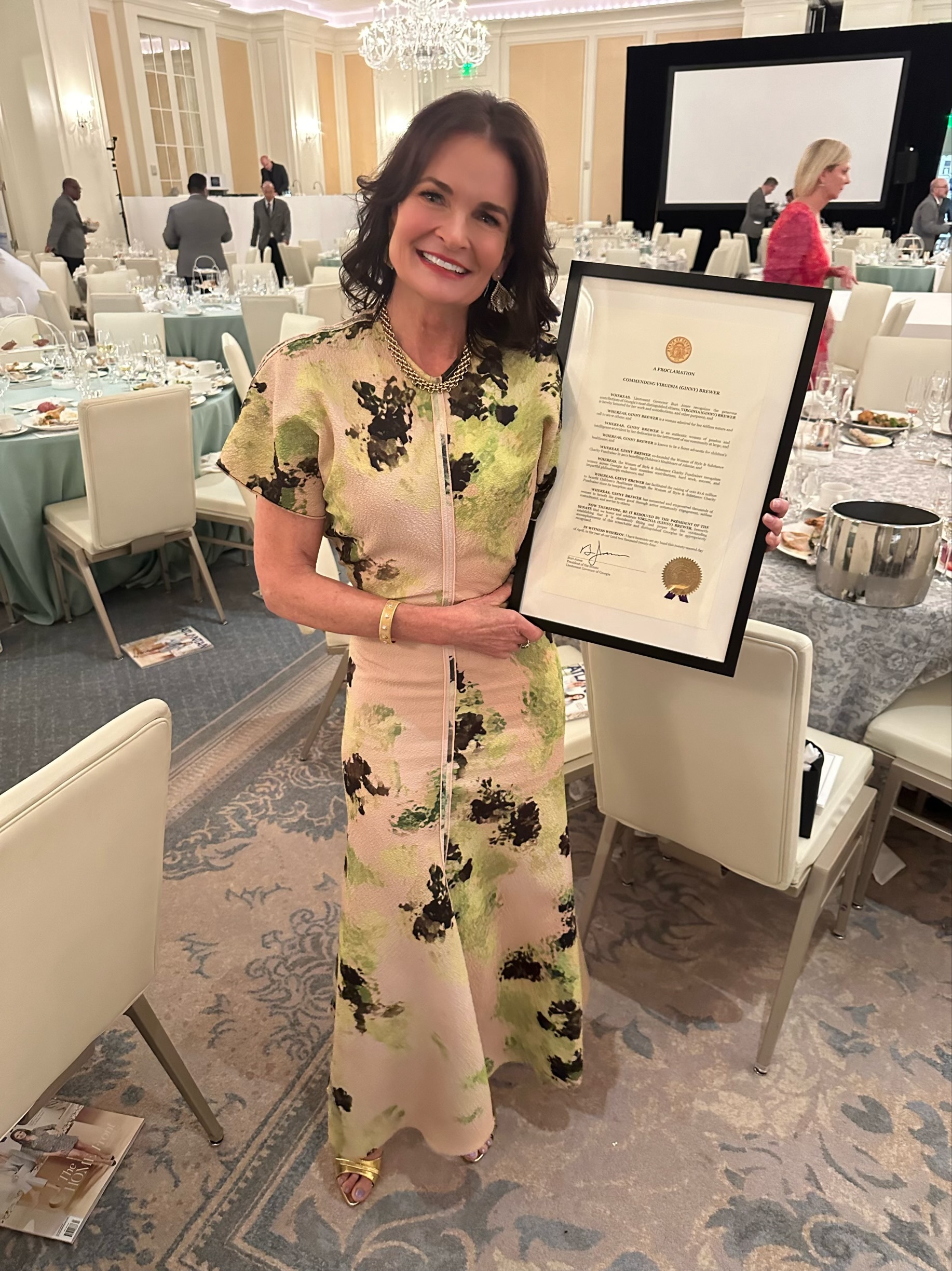 Ginny holding the Official Ginny Brewer Day Proclamation from April 2024