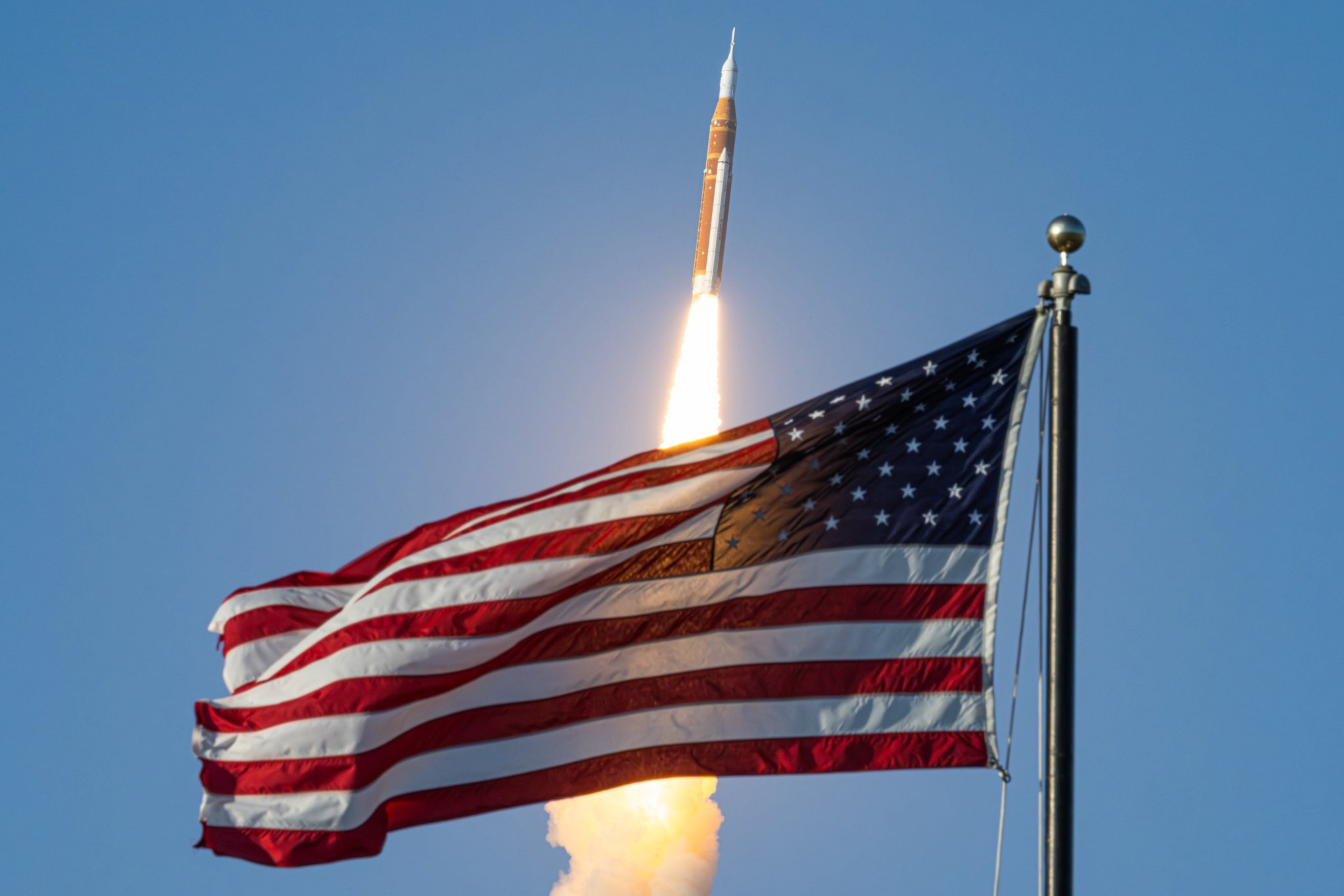 Artemis launch rising behind the American flag in Cape Canaveral, FL