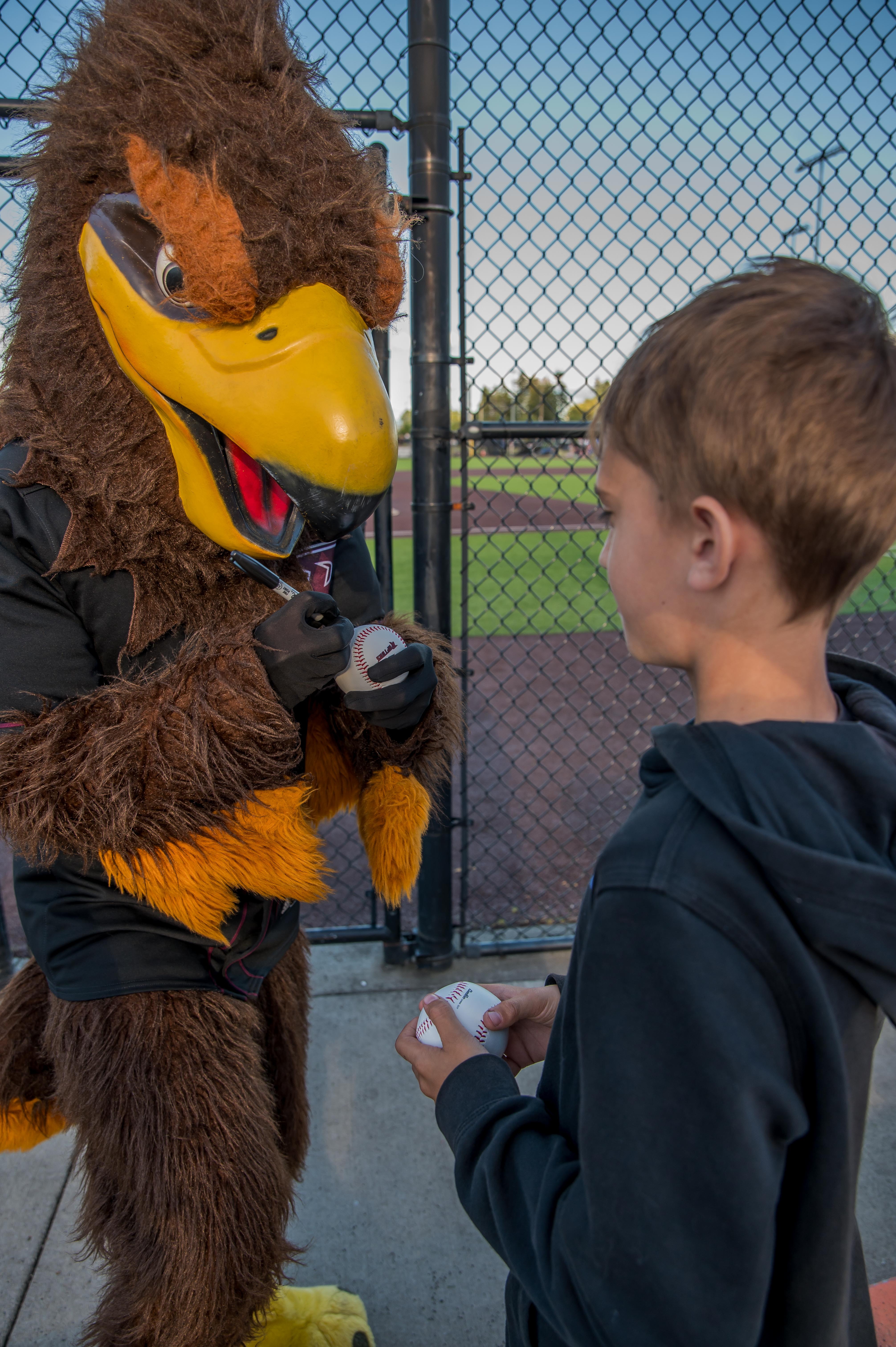 Rally the Raptor signs an autograph for a young fan before the start of a Ridgefield Raptors game.