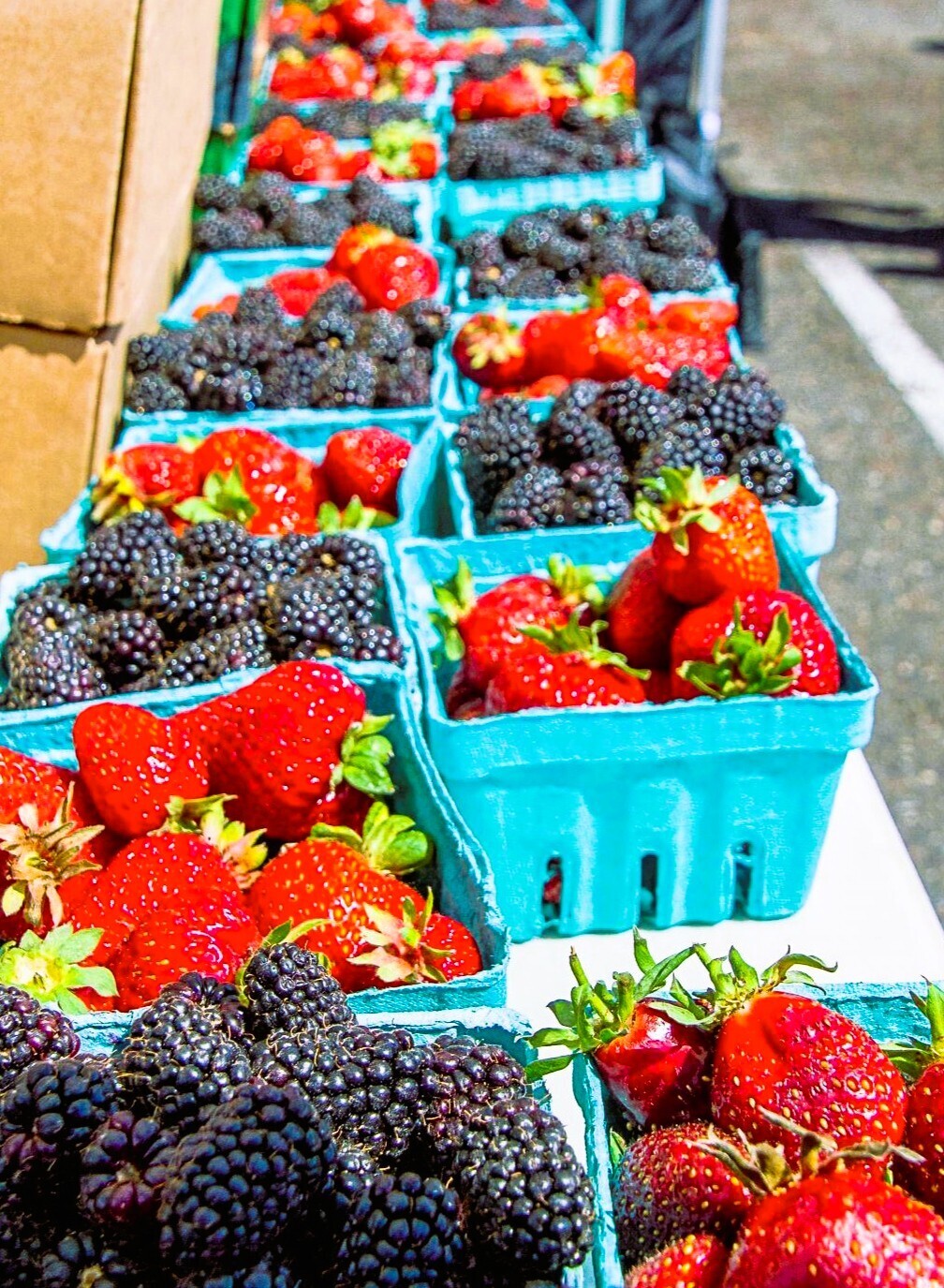 Shoppers browse locally grown produce, plants, strawberries, and blackberries at the Ridgefield Farmers Market.