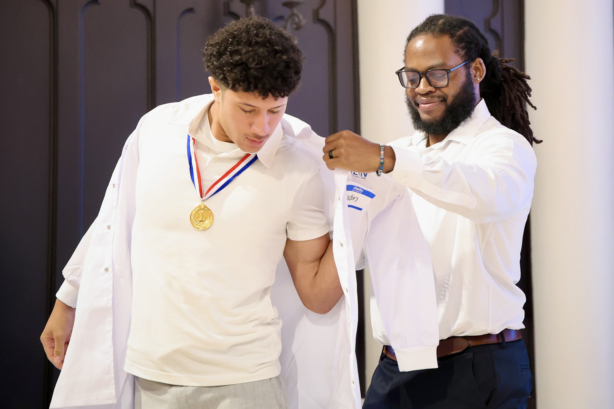 Desmond Brock presenting a student their white coat.